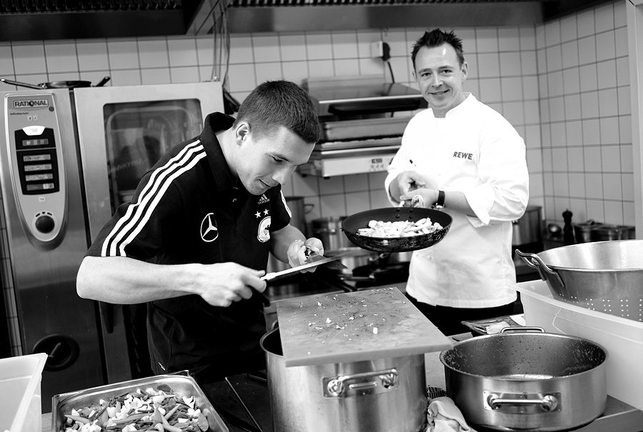 Spielerwechsel an den Herd – Lukas Podolski macht den Küchenassistenten für Holger Stromberg. Foto © Michael Agel