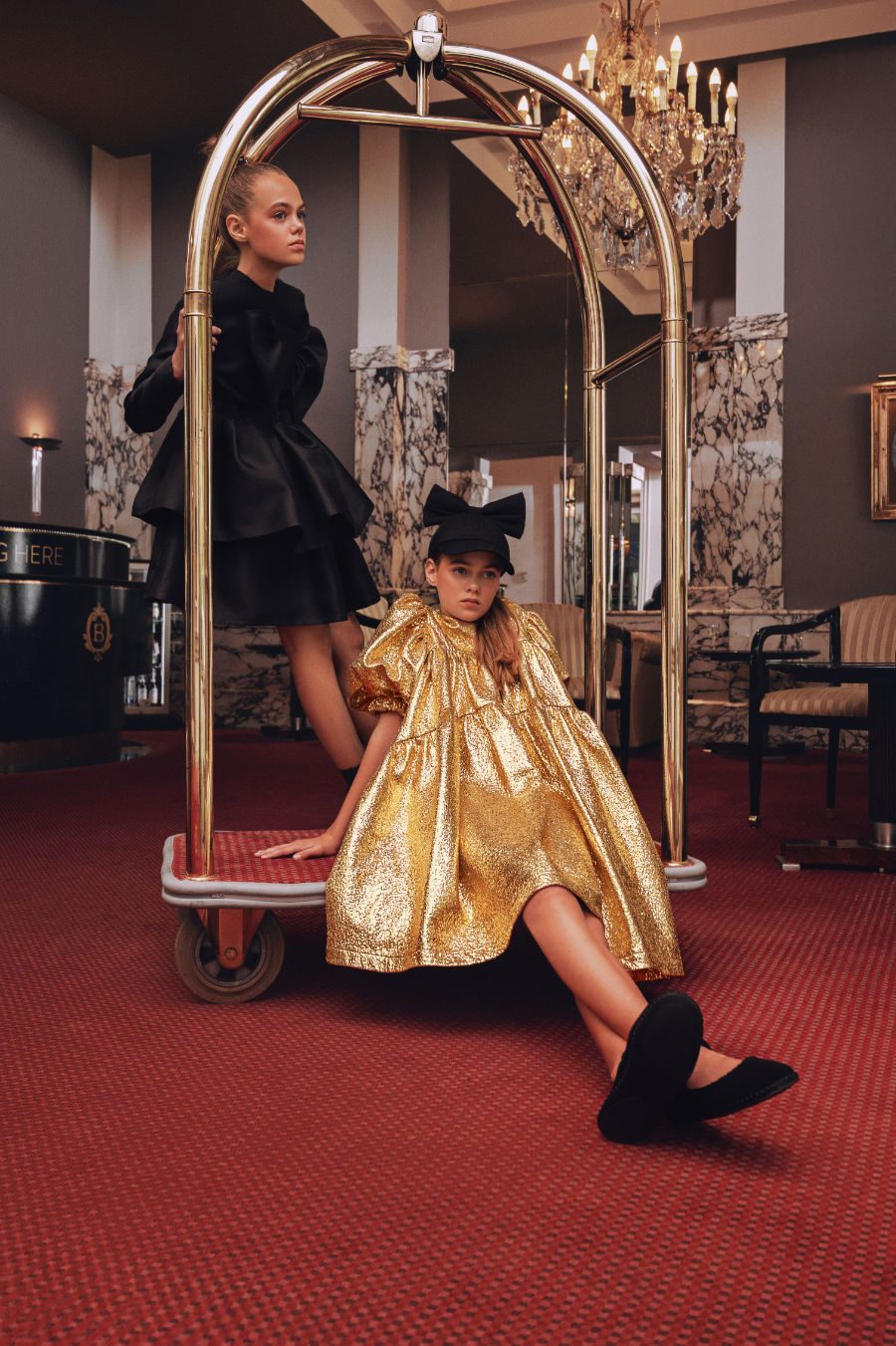 Smilla: Black Dress von CAROLINE BOSMANS, Socken von FALKE, Haargummi von MAMARADSCHA. Alma: goldenes Kleid und Bow Cap von CAROLINE BOSMANS, Mary Janes von MANGO. Foto © Valentyna Pugachova