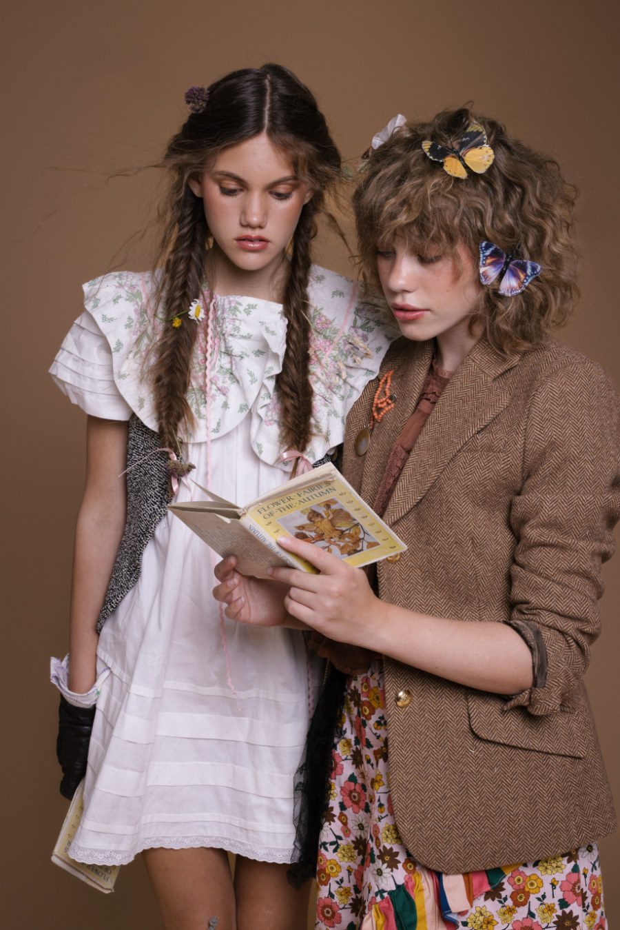Die ultimative Fairycore-Lektüre im Herbst? “Flower Faires of the Autumn” von Cicely Mary Barker! Passend dazu trägt Isabelle ein Kleid von VIVESSENCE BY LUNA, Weste von ZARA, Kragen von MAEVE CHERRY, Lederhandschuhe STYLIST‘S OWN. Elysia in einem Tweed Blazer von JOULES, Top von FREE PEOPLE, Rock von THE MIDDLE DAUGHTER